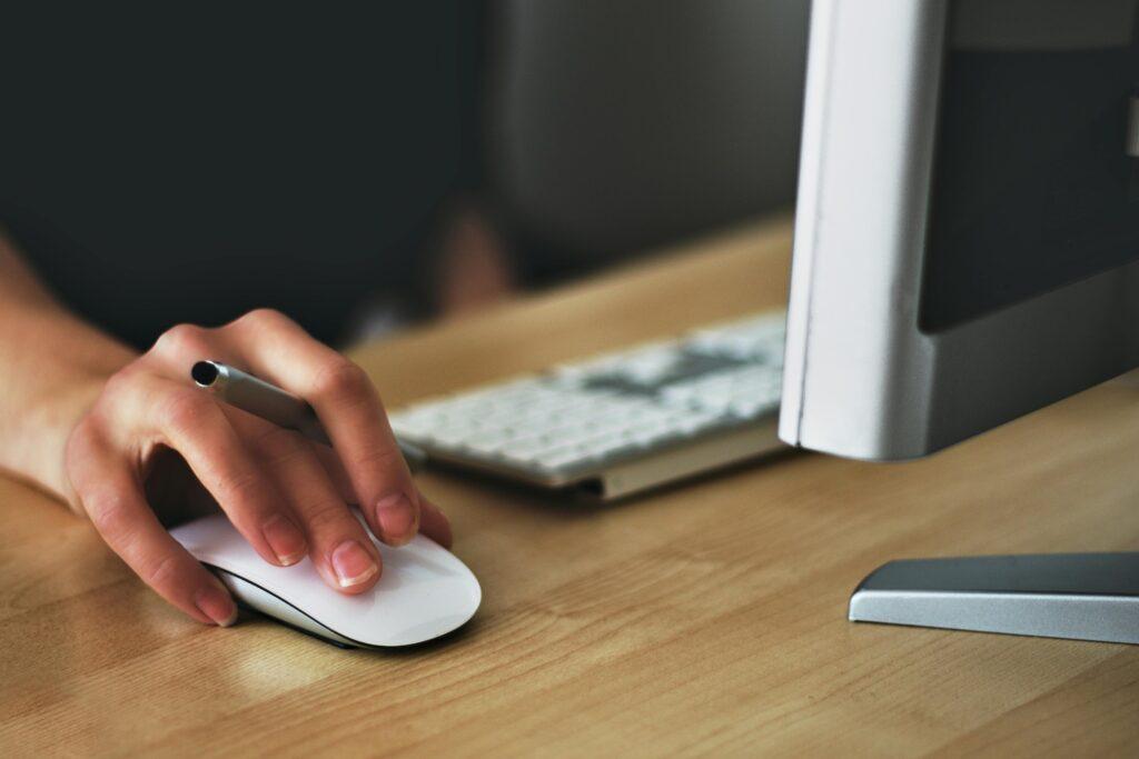 Hand an einer Computermaus – der Firmenname