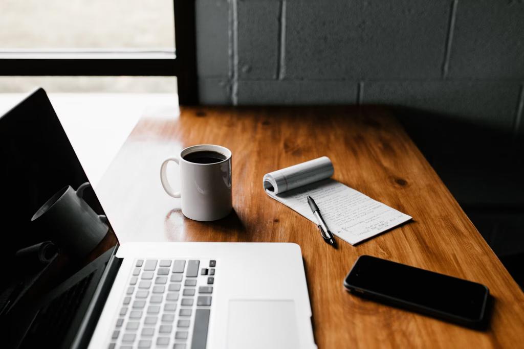 Schreibtisch von oben mit Laptop, Kaffee und Notizbuch – Hoop-Webinar zu digitalen Gründungen und Mutationen